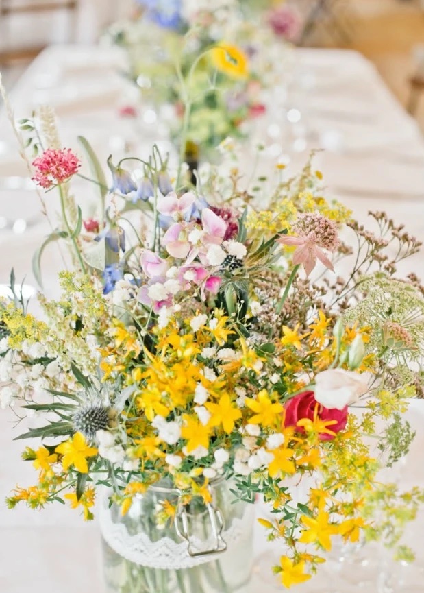 Bouquet de fleurs des champs jaunes et roses dans un bocal de verre, en centre de table
