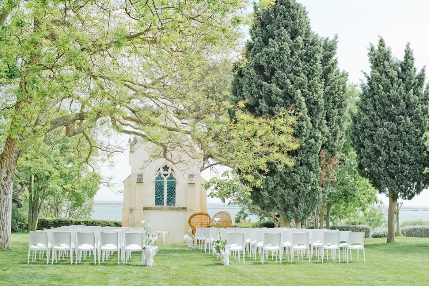 Cérémonie laïque en plein air devant une chapelle, rangées de chaises blanches sur l'herbe