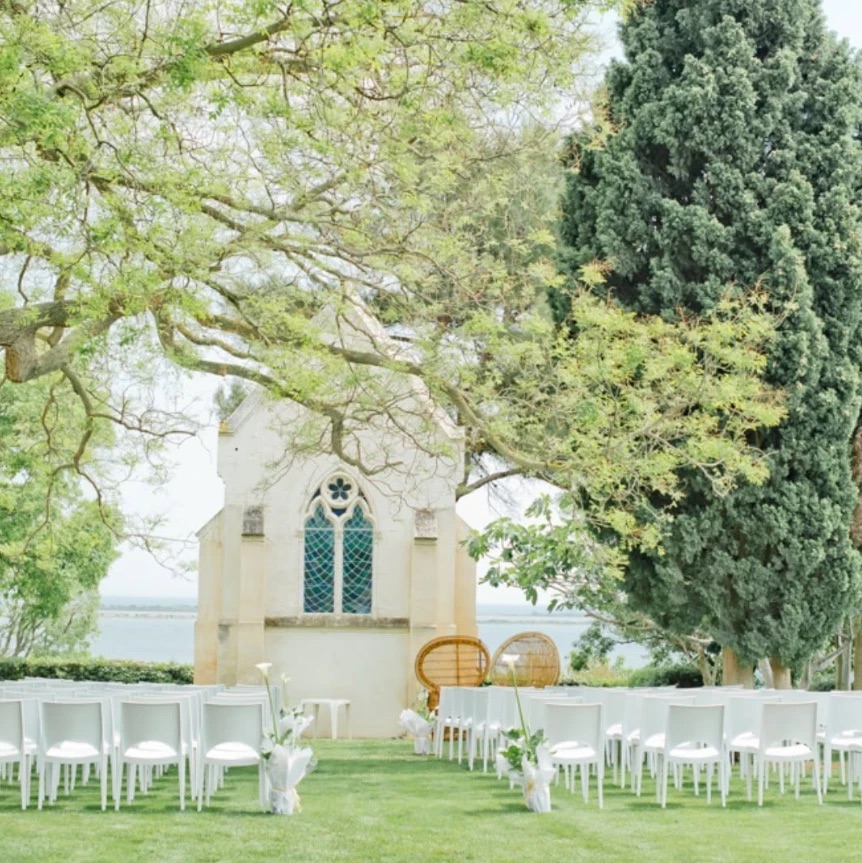 Chaises blanches alignées devant une chapelle de pierre, cérémonie laïque en plein air face au lac