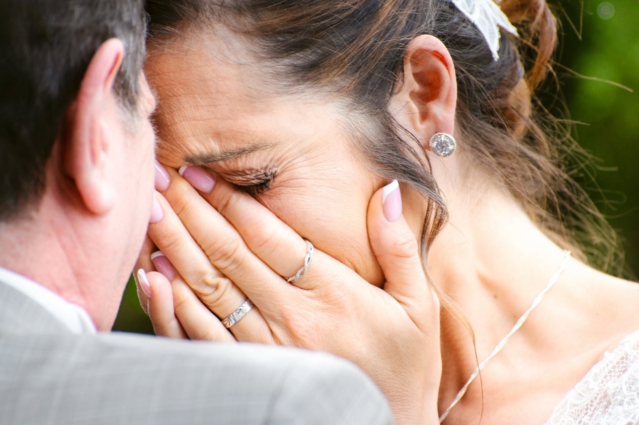 La mariée émue, les mains sur le visage, réconfortée par son époux