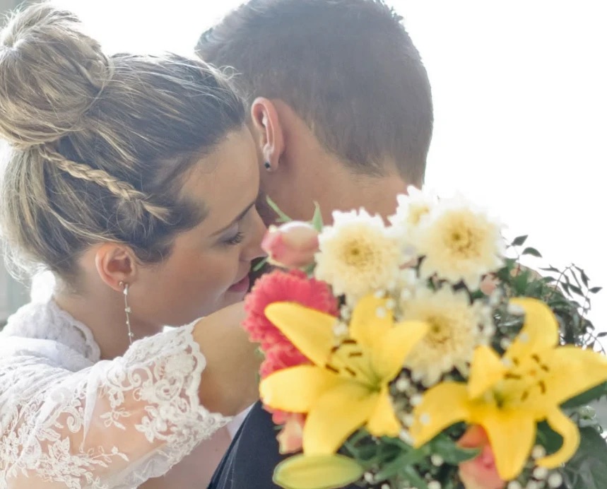 La mariée blottie contre son époux, un bouquet de lys et de dahlias au premier plan